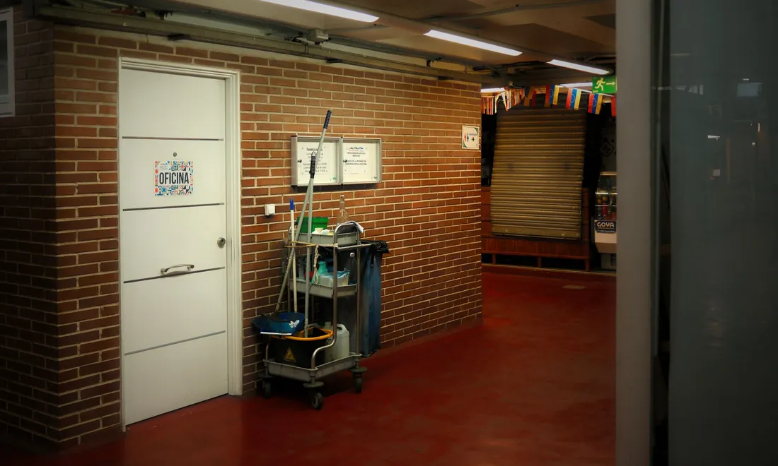 Reinigungswagen in einem Flur mit Backsteinwand und rotem Boden